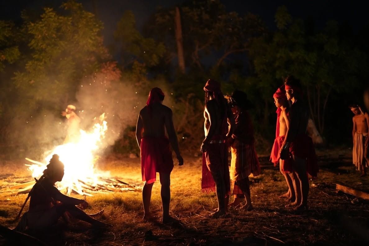Figures around a large bonfire at night