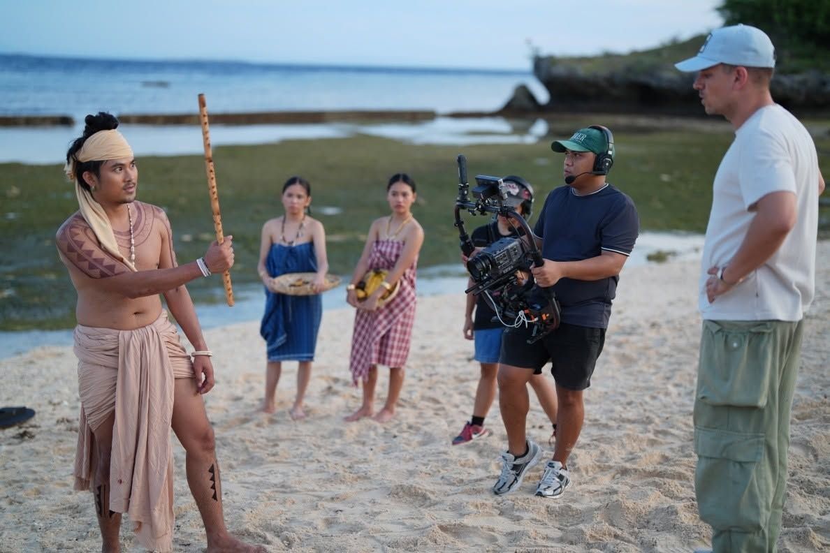The crew with a gimbal camera and actors on the sand at the shore