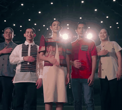 Five delegates in barong, filipiniana and a red shirt stand at night and place their hands on their hearts