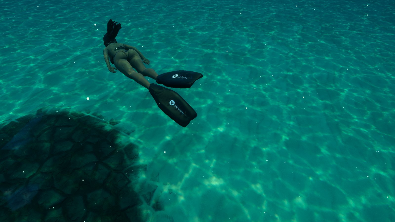 The freediver from above, the Alchemy mark on both fin blades over the caustic light on the sand
