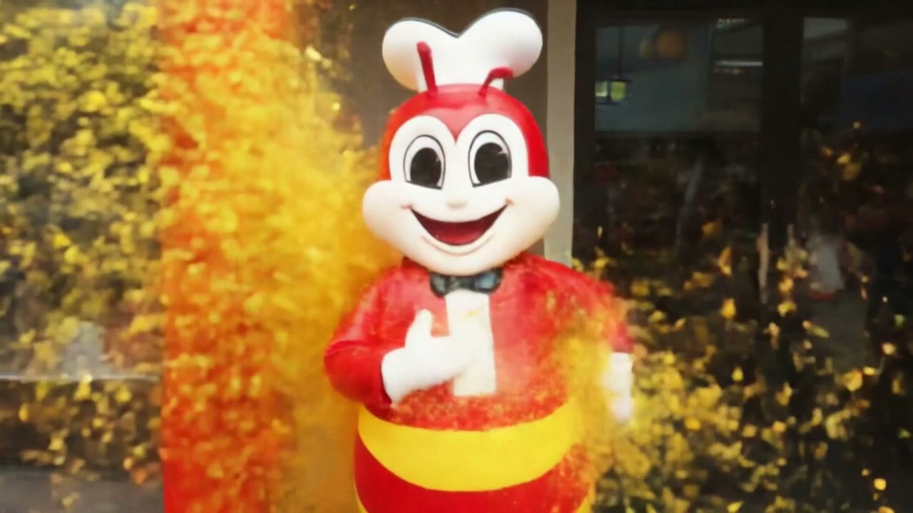 AI video still: the Jollibee statue in a burst of yellow and red particles