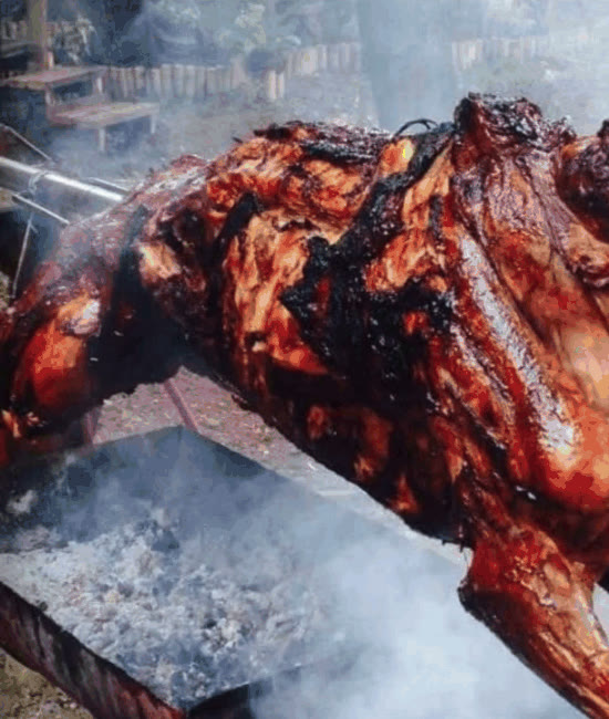 Lechon baka, a whole beef roasting on a spit over smoking charcoal