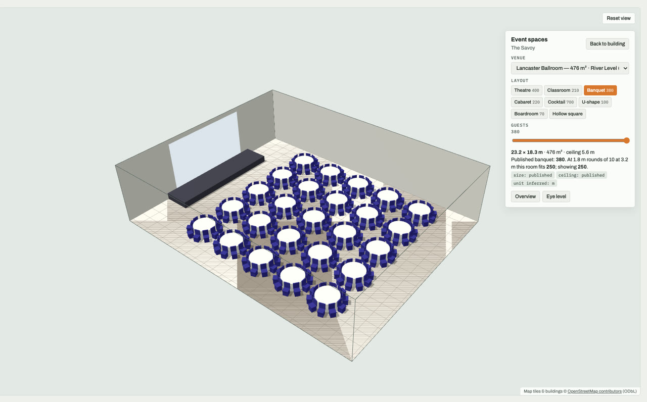 Lancaster Ballroom at The Savoy, London, drawn to scale in 3D (23 × 18 m, 476 m², ceiling 5.6 m) and set for a banquet layout of 380 guests: navy chairs around white round tables facing a stage and screen. Event-space model by Budots Media.